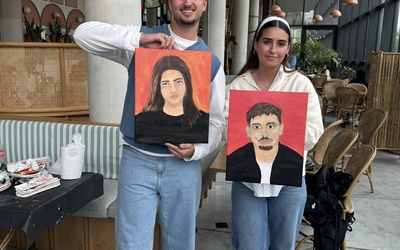 Personnes en train de peindre le portrait de leur partenaire lors d’un atelier créatif et convivial à Paris.