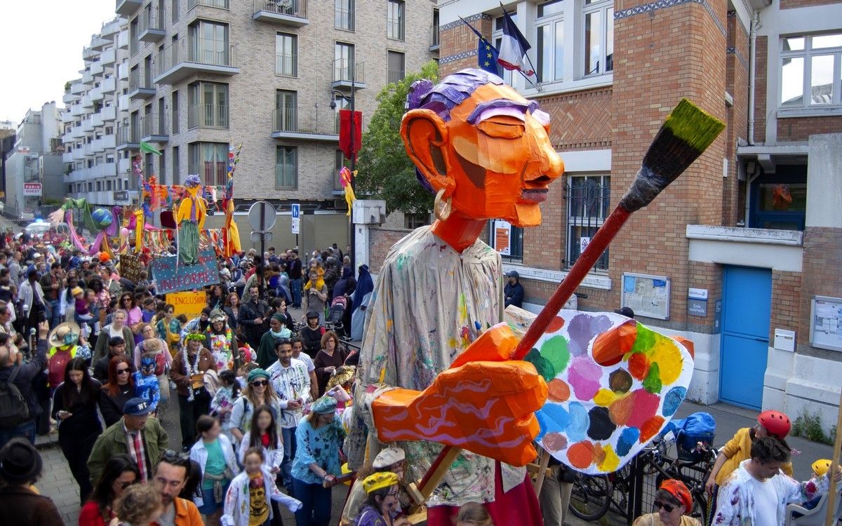 Lors d'un carnaval, un Géant de couleur orange, habillé d'une chemise de peintre, tient un immense pinceau dans la main droite et une immense palette de couleur dans la main gauche. Il est au milieu d'une foule déguisée, suivi d'autres chars.
