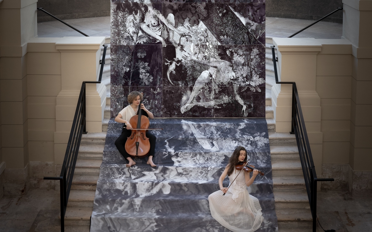 Performance où résonnent violon et violoncelle, autour d'une gravure monumentale