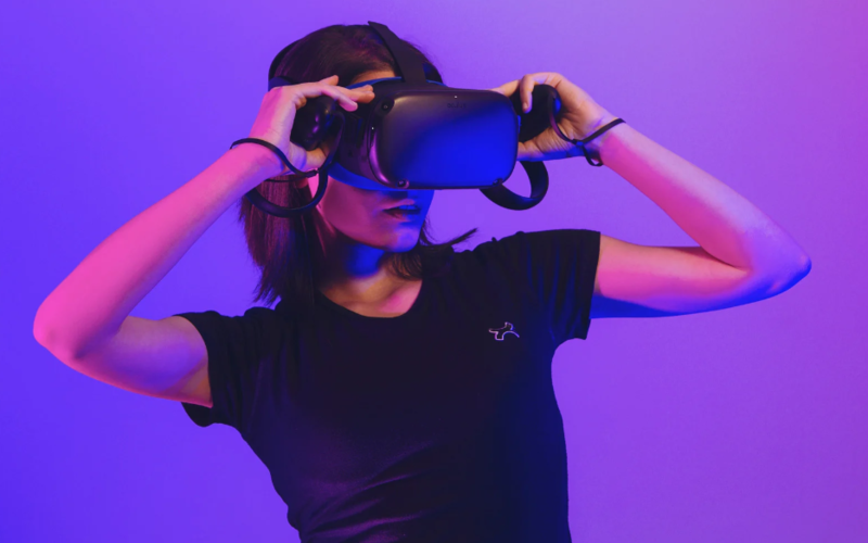 Une personne utilise un casque VR, sous un fond et une lumière violets