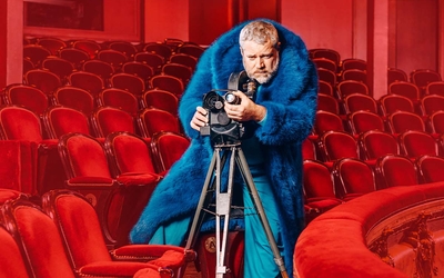 Homme derrière une caméra, portant un gros manteau de fourrure bleu