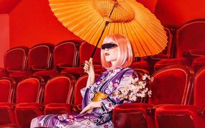 Femme assise dans les fauteuils d'un théâtre, habillée en Geisha avec des lunettes futuristes