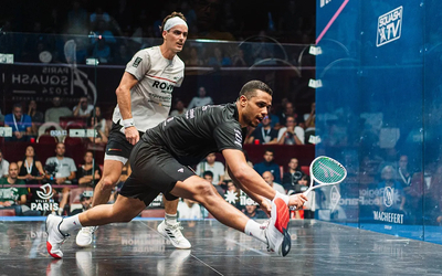 Deux joueurs professionnels de squash s’affrontent sur un court vitré devant un public lors d’un tournoi international à Paris.