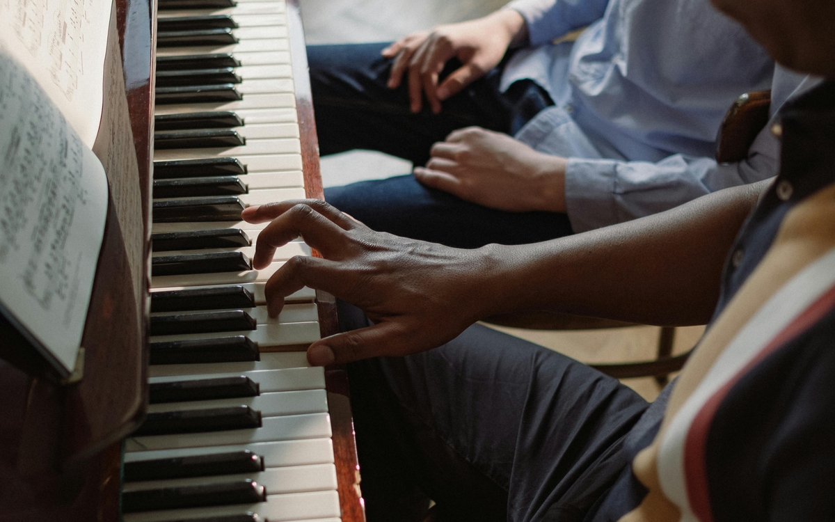 Deux homme, un élève et un professeur sont en train de faire du piano 