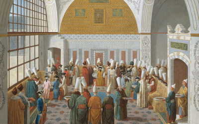 Riche salle d'un palais oriental où se mêlent locaux et occidentaux. Ces derniers  servent une enfilade de plats copieux à leurs invités. 