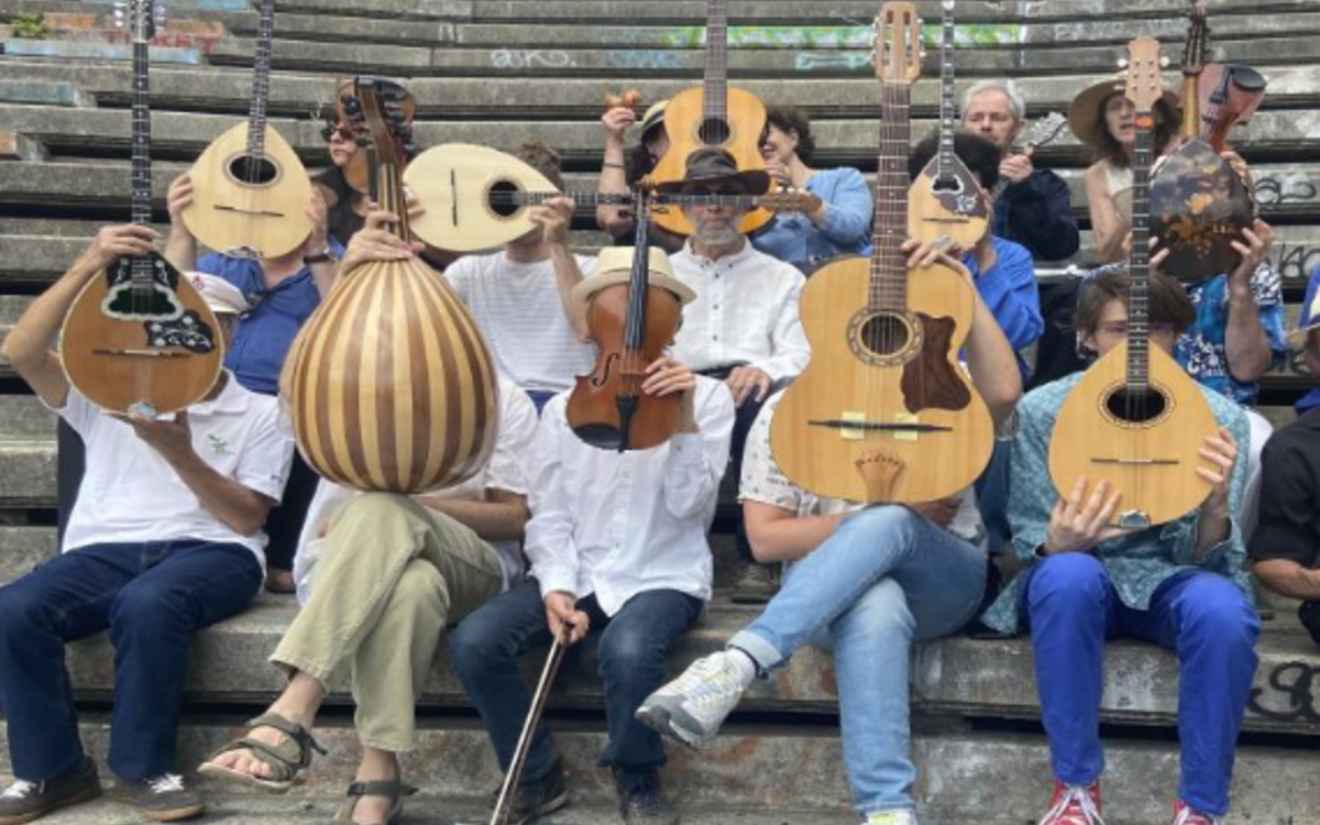 Photo couleur d'une dizaine de personnes tenant des instruments de musique grecque traditionelle devant leur tête