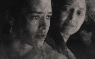 L'image présente deux personnes en plan fixe, avec un focus sur leurs visages. Le visage au premier plan, situé à gauche de l'image, regarde vers la droite avec des yeux inquiets et les sourcils froncés. Le second visage situé en arrière plan, à droite, regarde le premier visage à sa gauche un regard doux et compatissant. Ni l'un ni l'autre n'a l'air de parler.