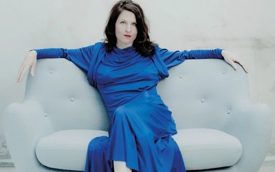 Vanessa Wagner en robe bleue assise sur canapé gris