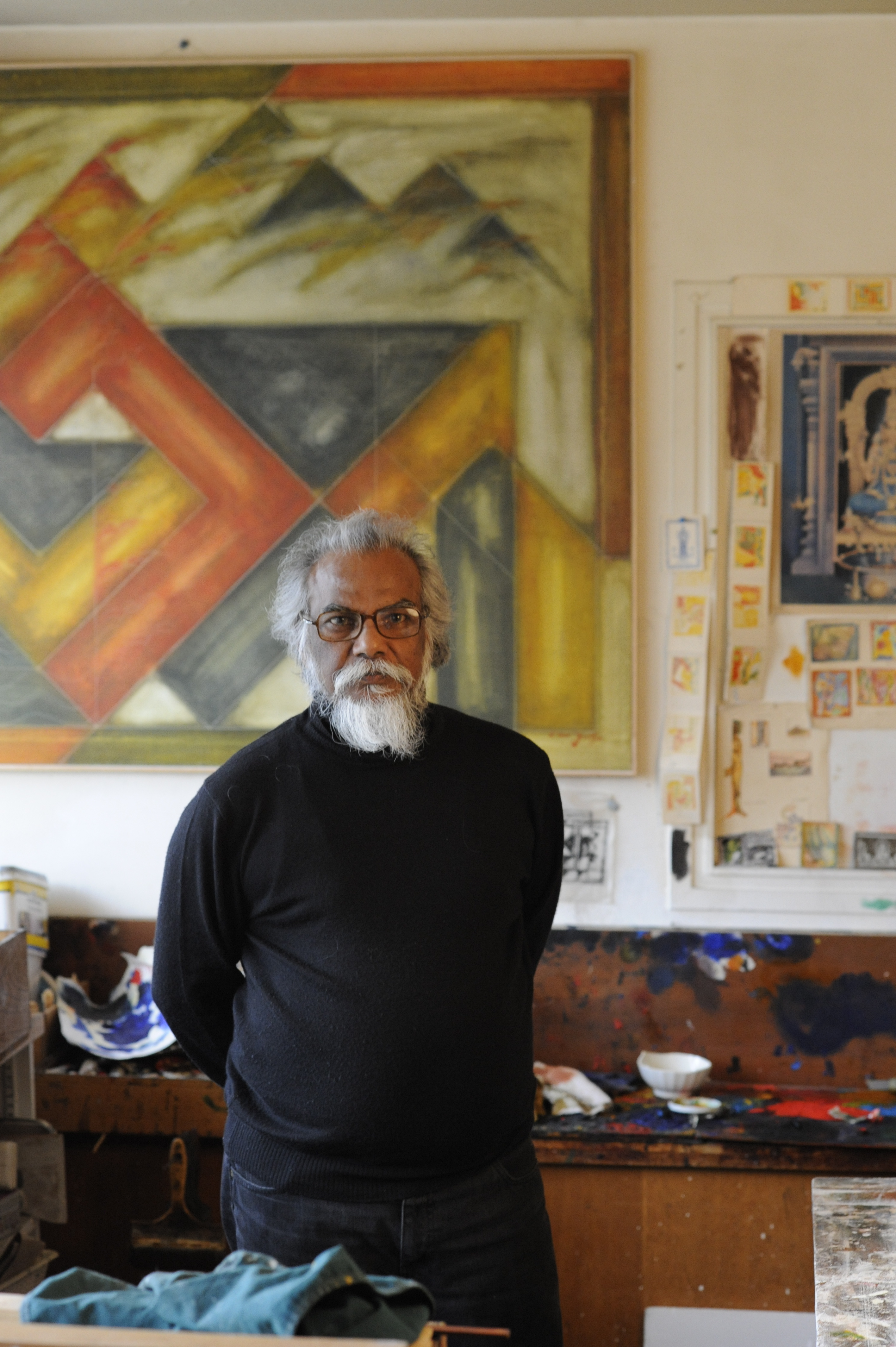 Portrait d'Akkitham Narayanan dans son atelier parisien à l'occasion de son exposition à la Galerie AB. L'artiste peintre indien, figure majeure de l'abstraction géométrique contemporaine, pose au milieu de ses œuvres, dans un espace de création lumineux où se dévoilent son univers inspiré de l'art tantrique, de la géométrie sacrée et de la couleur. Ce portrait d'atelier met en lumière le dialogue entre l'artiste, son processus créatif et plusieurs décennies de recherche picturale.