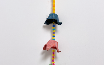 Photographie d'une suspension murale faite à partir de boîtes d'œufs peintes et de perles, le tout de différentes couleurs : rose, jaune, bleu, vert et orange.
