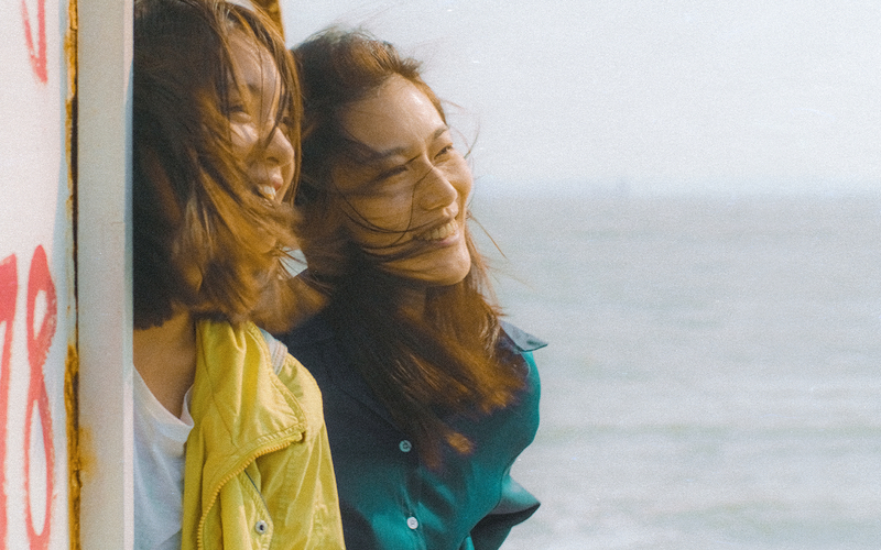Deux jeunes femmes sourient face à la mer dans une scène du film Out of Place.