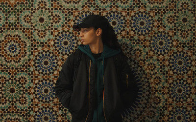 Capture du film « La Petite Dernière » représentant une femme brune de profil devant un mur de mosaïque