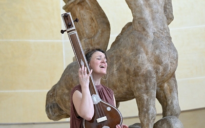 Une femme avec une guitare devant des sculptures du Musée Bourdelle