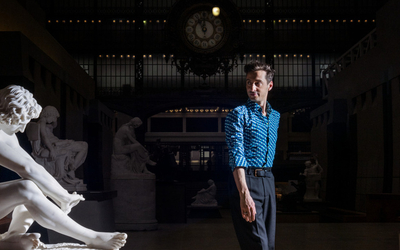 Photographie de Thomas Jolly face à une sculpture du Musée d'Orsay 