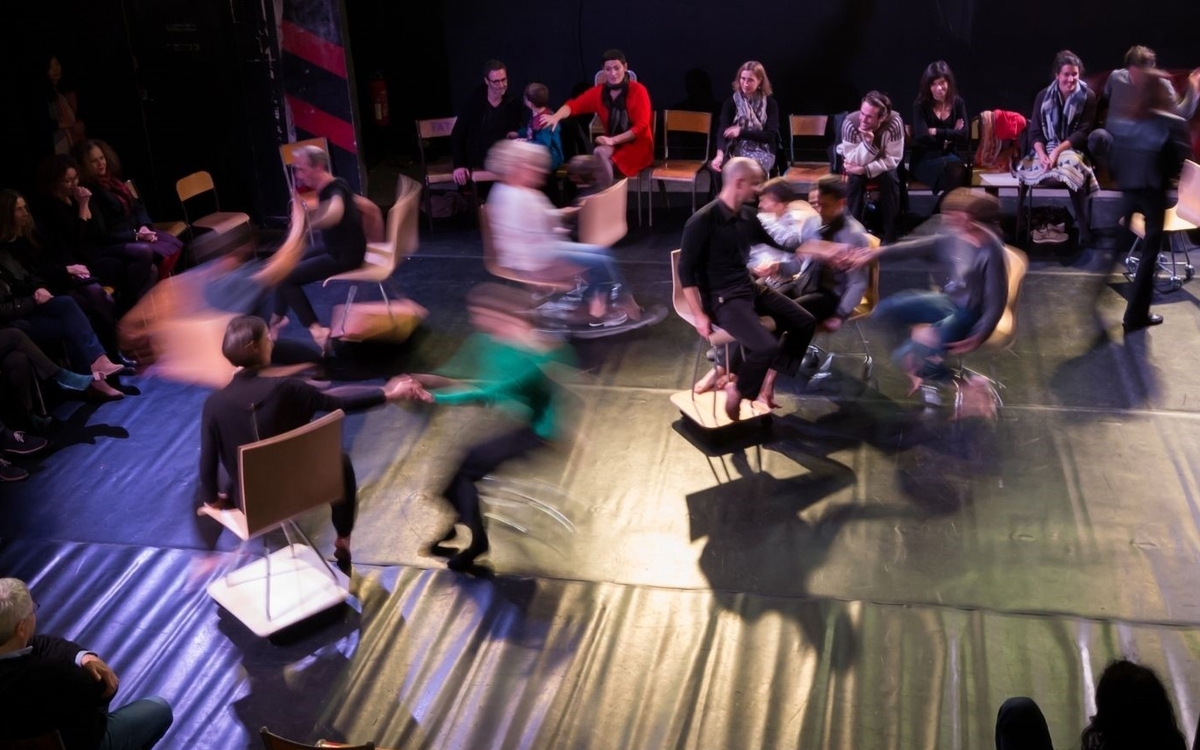 Prise de vue en hauteur d'un bal : on y voit des personnes en mouvement sur des chaises
