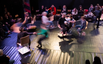 Prise de vue en hauteur d'un bal : on y voit des personnes en mouvement sur des chaises