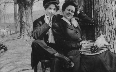 Photographie en noir et blanc représentant un couple de femmes près d'un arbre