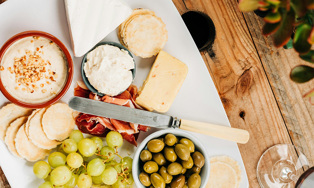 planche apéro avec fromage, charcuterie, olives et raisins