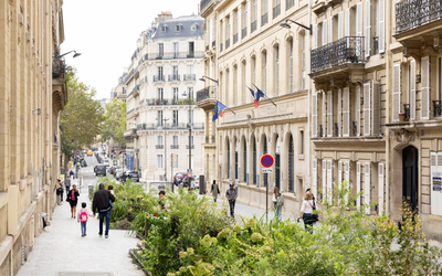 Rue végétalisée de l'arrondissement, devant une école, avec des enfants et des adultes qui marchent