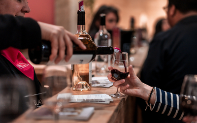 photo d'un bar à vin où une vigneronne de l'AOC Blaye Côtes de Bordeaux sert un verre de vin rouge à un client