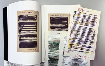 Livre de Lucien Suel (le livre des poèmes express), présenté ouvert avec des feuilles libres pour montrer le procédés du caviardage