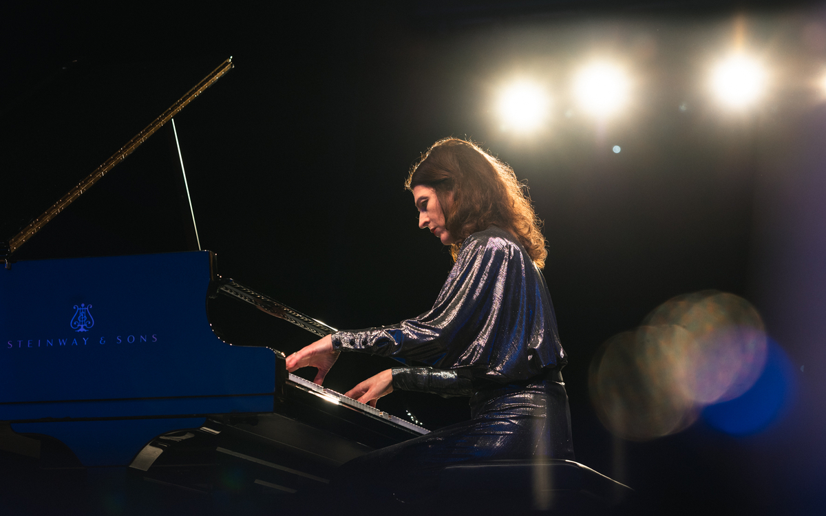 Photo de la pianiste Vanessa Wagner sur scène, au piano, robe bleue foncée à paillettes