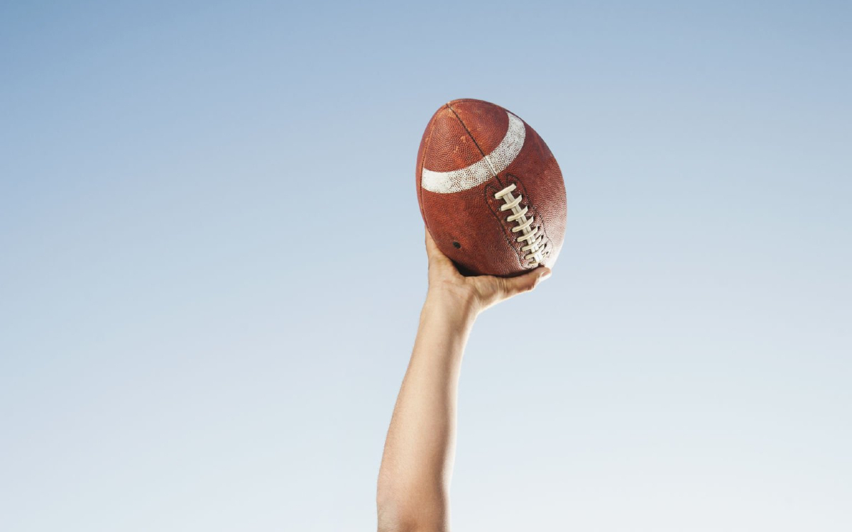 Photo d'un bras lançant un ballon de football américain.