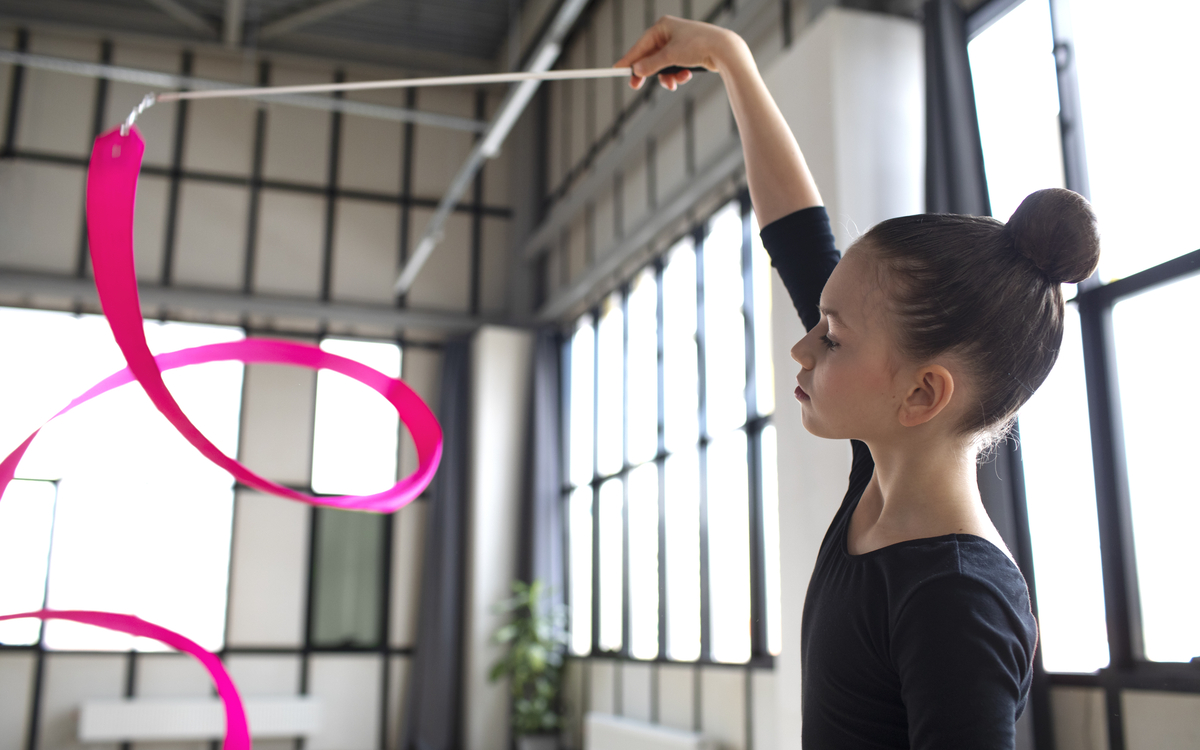 Jeune fille qui s'entraine à la gymnastique rythmique avec un ruban rose