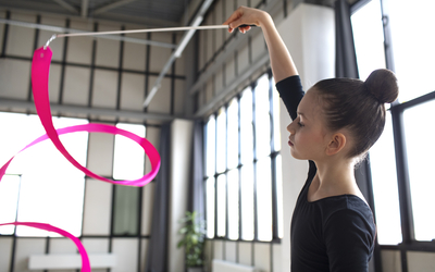 Jeune fille qui s'entraine à la gymnastique rythmique avec un ruban rose