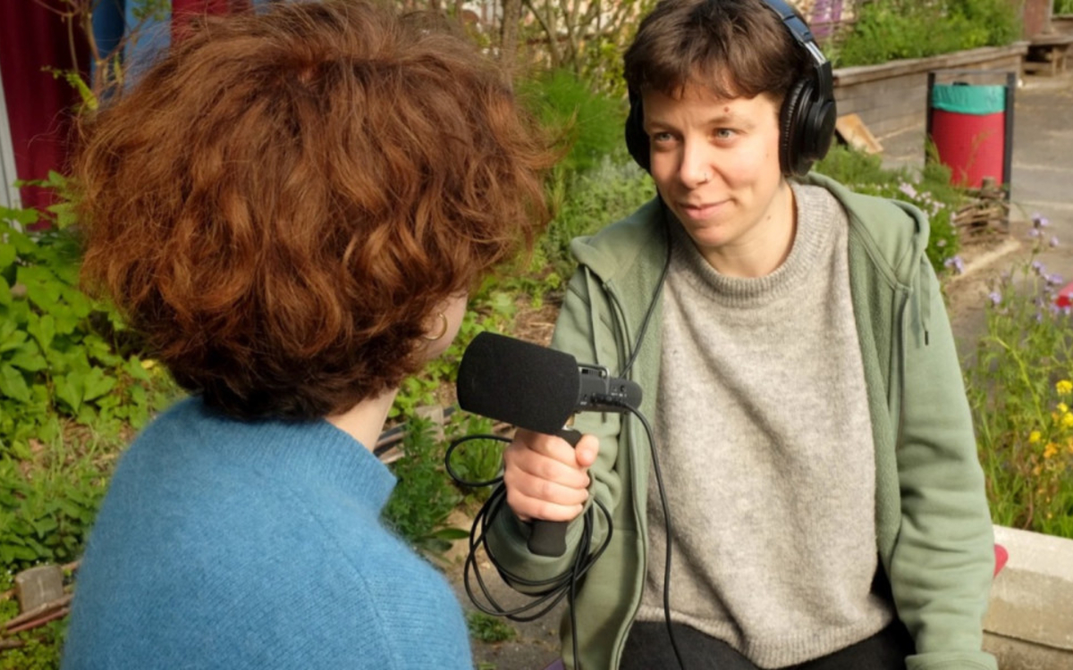 2 jeunes en train de s'interviewer, fond de verdure dans un parking