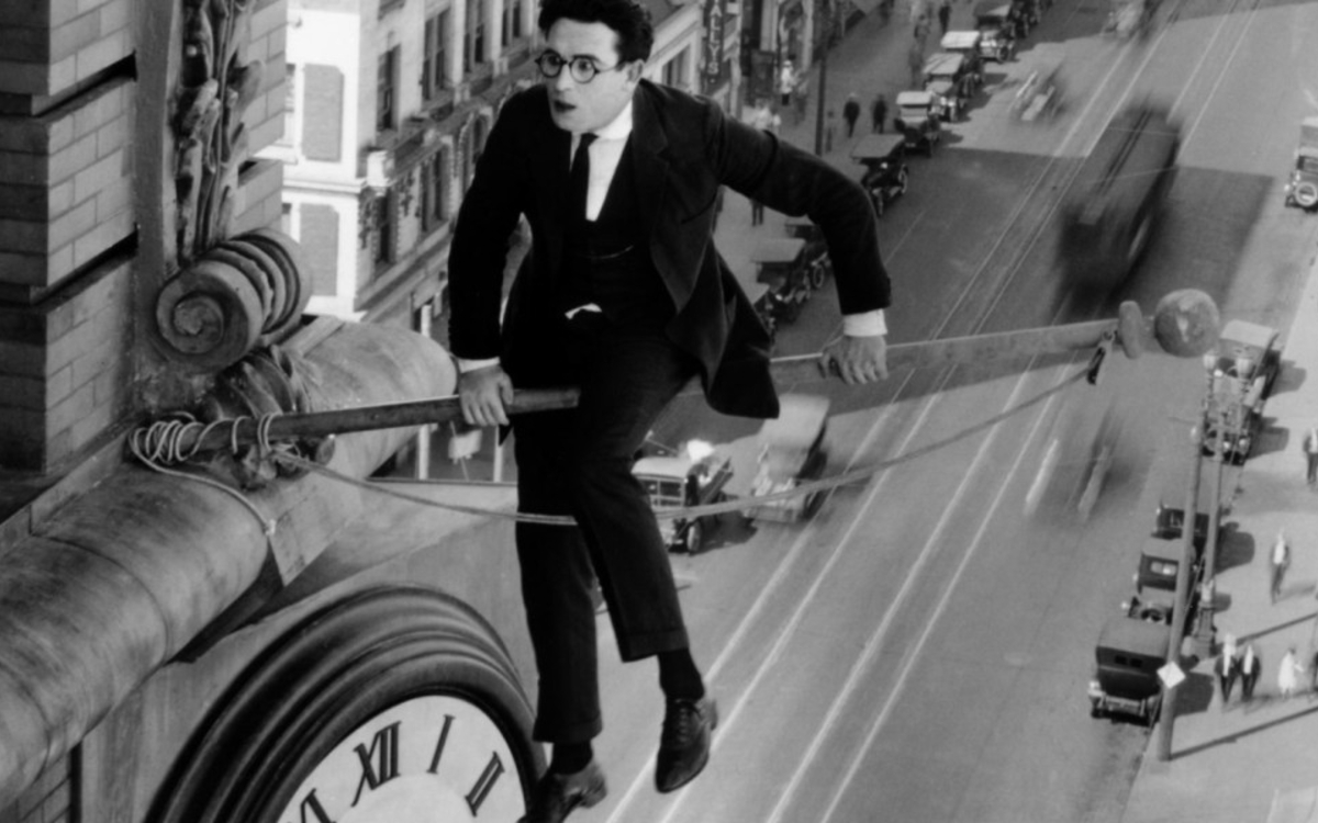 Un homme en costume sur une façade d'immeuble au dessus du vide de la rue