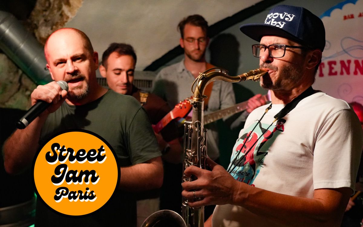 groupe de musique funk qui joue sur une scène avec un saxophoniste un chanteur, un bassiste et un guitariste