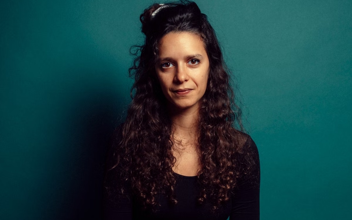 PHOTO DE Lou Welgryn, intervenante pour Vert Le Media et Data For Good, elle sourit face caméra sur un fond bleu vert